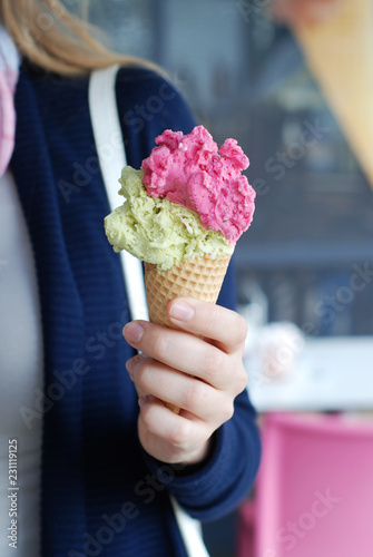 Hand holding colourful ice-cream in a cone closeup