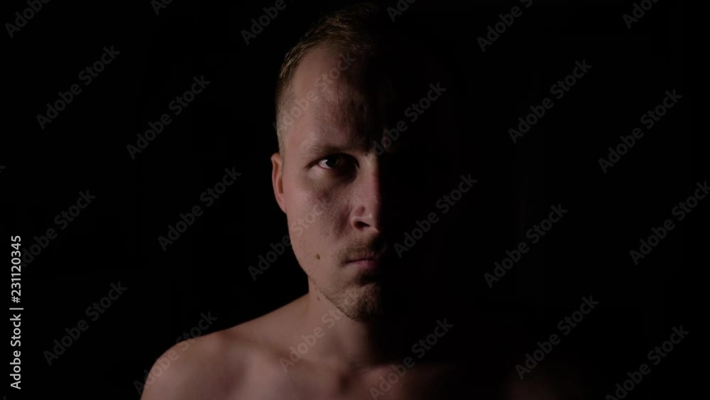 Angry man in the dark. Only half of the face is highlighted. Angry man in the dark. Only half of the face is highlighted.