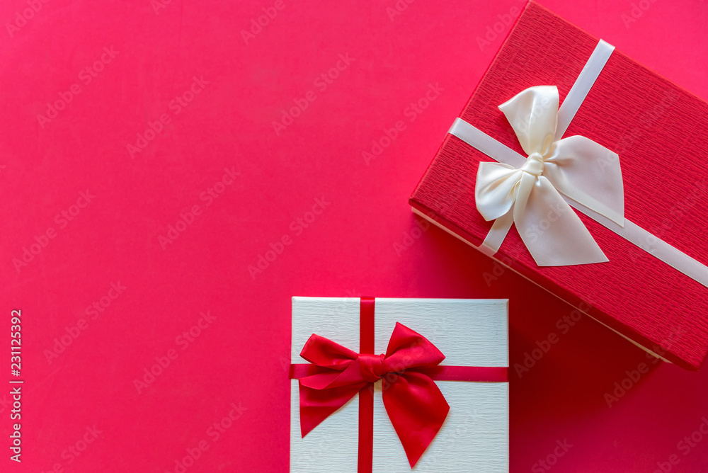 Christmas Day gift box with a red bow on red wall background, copy space. Merry Christmas and New Year Concept.