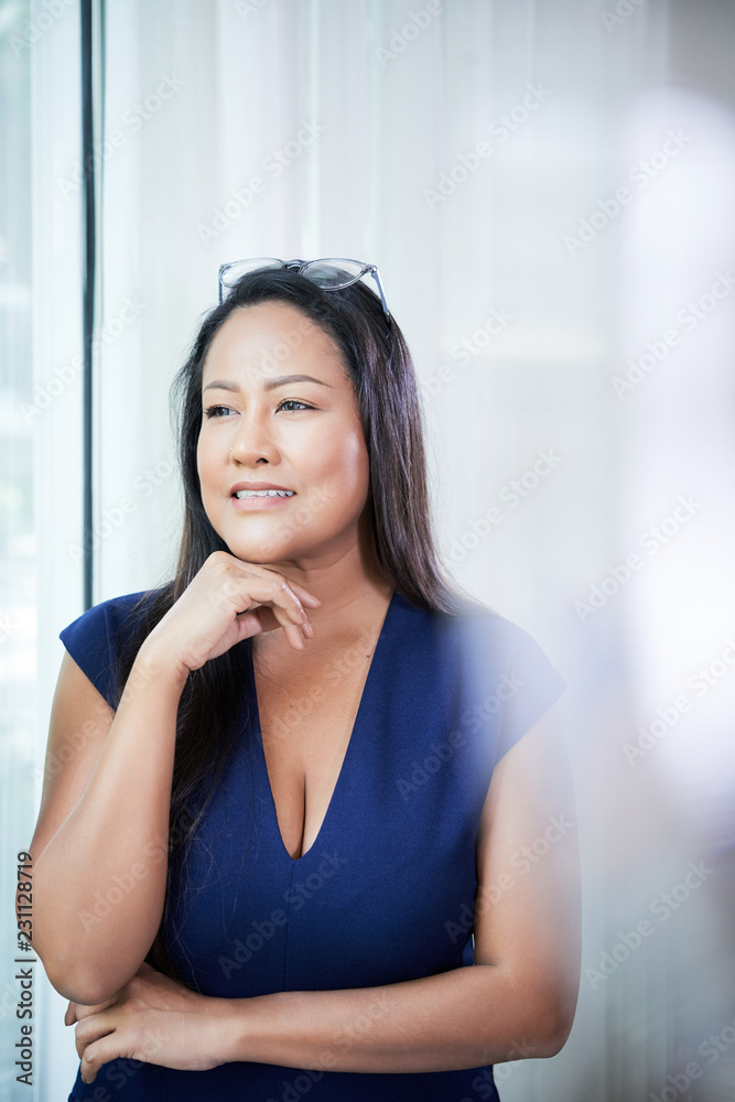 Elegant Thai woman in dress touching chin in thoughts looking away pensively Elegant Thai woman in dress touching chin in thoughts looking away pensively