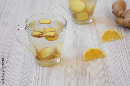 Homemade ginger tea with lemon on white wooden background, side view. Closeup.