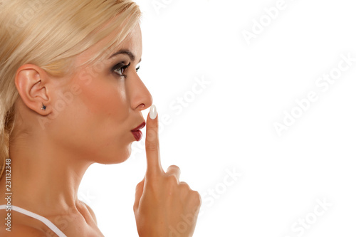 Profile of beautiful girl with finger over her lips on white background