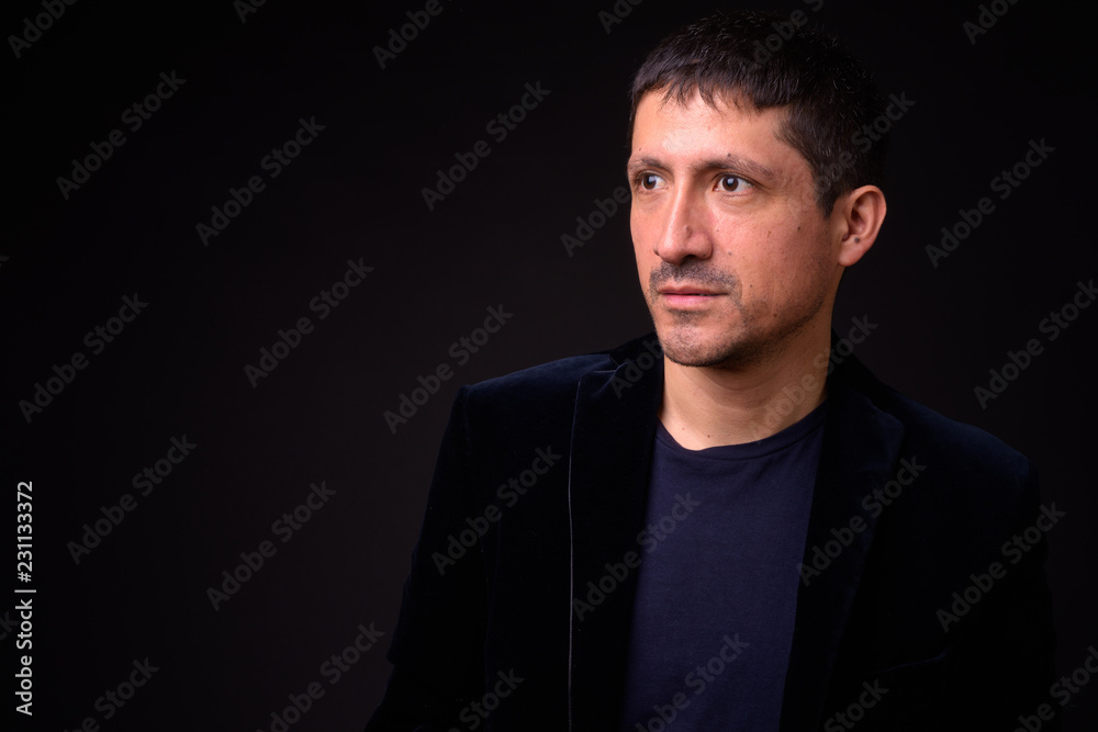 Fototapeta premium Portrait of Hispanic businessman against black background