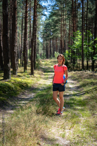 Young woman having a healthy walk in the green forest. Active, happy lifestyle. Summer, warm day. Stay fit.
