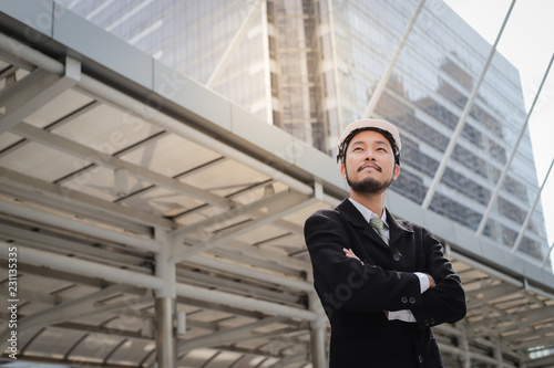 Successful young asian engineer man standing over modern building background