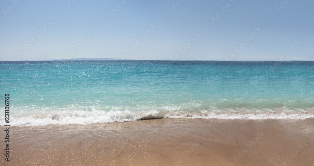 Seashore with wet sand and turquoise waters.