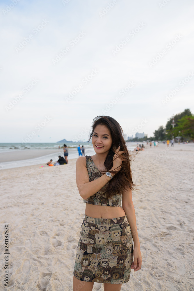 Young happy beautiful Asian woman smiling and standing at the sh