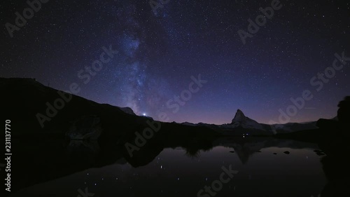 4K time lapse of Beautiful sky Color of the Matterhorn pyramid with milky way and all the star at Stellisee lake. Great reflection night scene in Swiss Alps, Zermatt, Switzerland, Europe