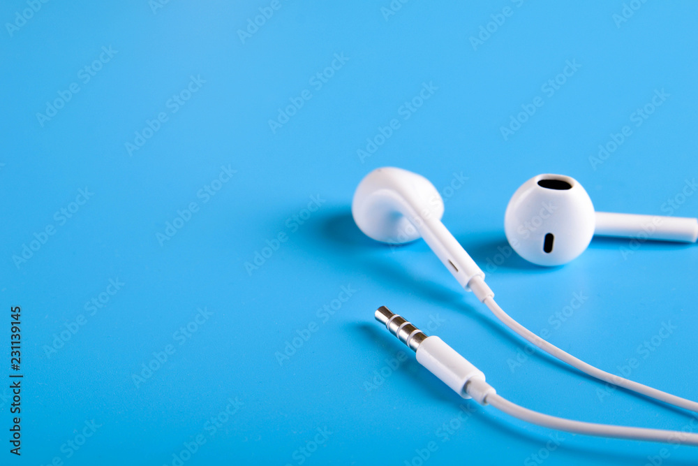 Mobile headphones of white color on a blue background in light colors with a place for text , copyspace. Top view.
