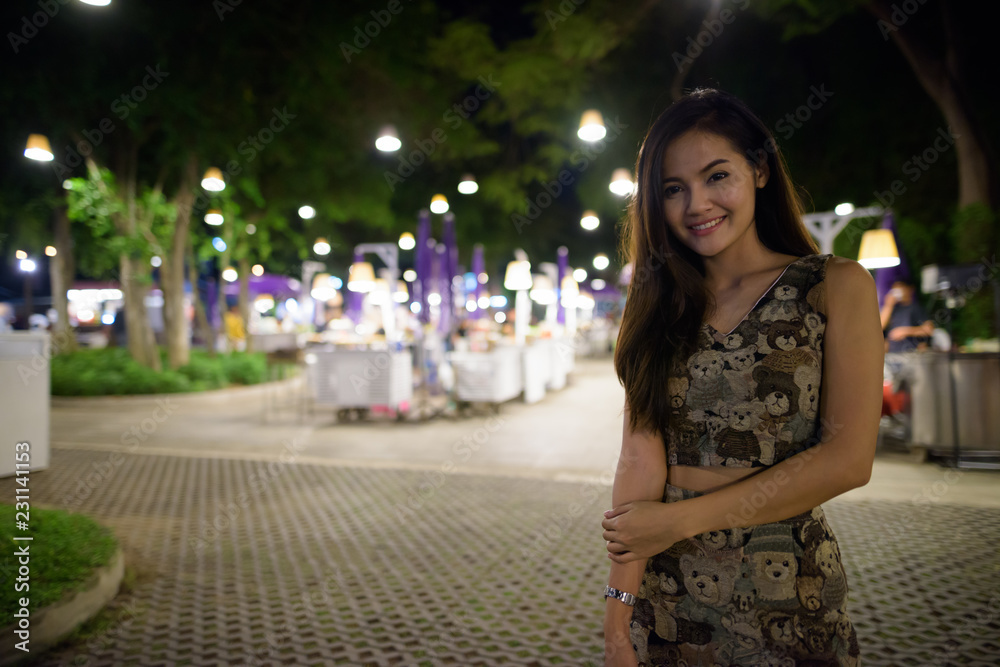 Young happy beautiful Asian woman smiling against scenic view of