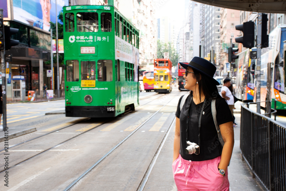 Fototapeta premium Tajska kobieta idzie na dworzec autobusowy na wycieczkę tramwajem retro i vintage w Hongkongu w Chinach