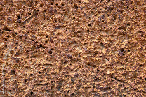 Rough sand stone texture. Porous orange stone closeup. Weathered grungy surface photo background.