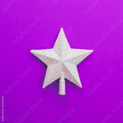 Creative Christmas shiny white star on purple background. Minimal flat lay concept.