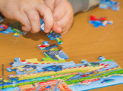 Baby hands assemble the puzzle on the table