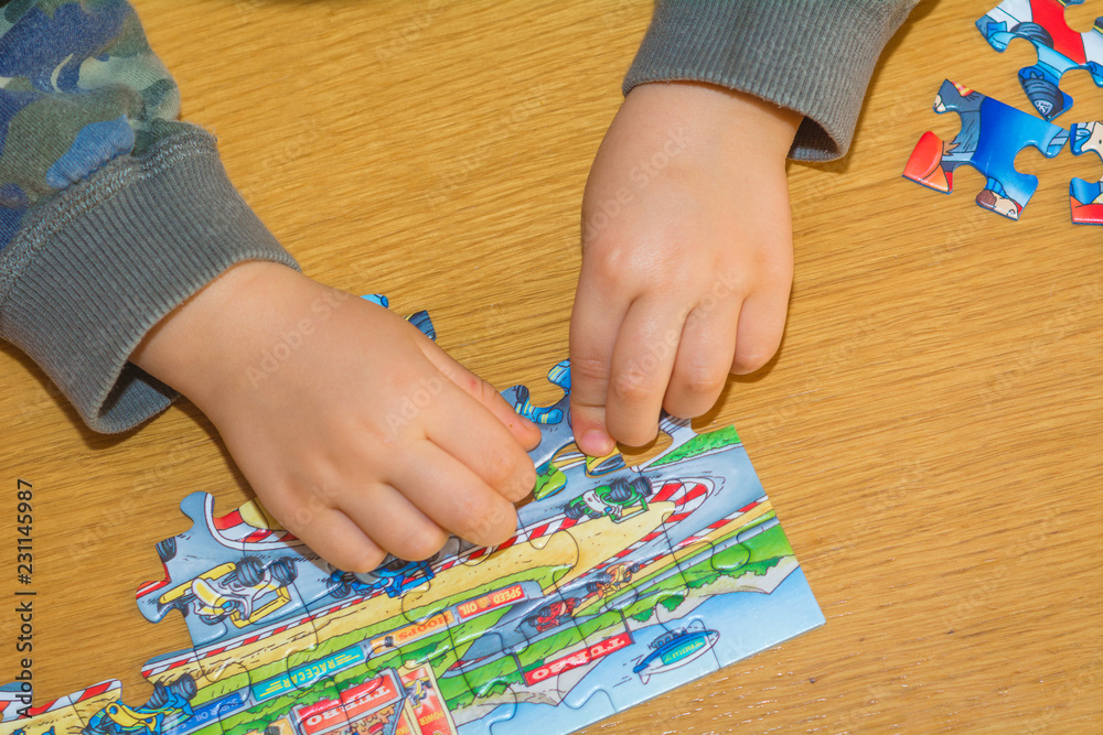 Obraz premium Baby hands assemble the puzzle on the table