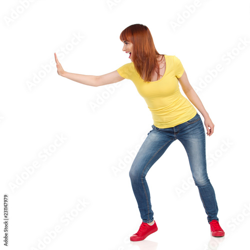 Side View Of Excited Young Woman Pushing Something With One Hand