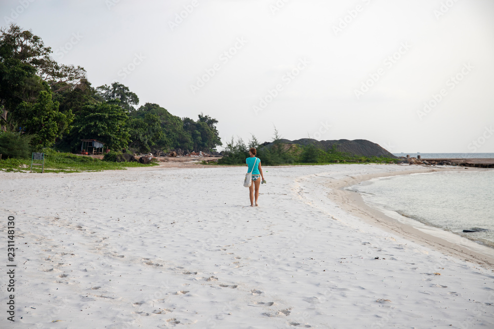 Lonely tourist on white sand beach by sea. Sole female tourist. Summer vacation on tropical island.