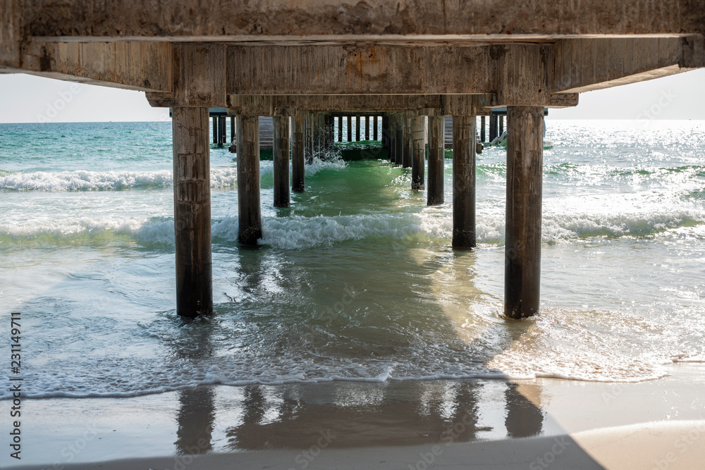 Sea water and beach view under long pier. Marine travel facility romantic view. Sunny day on tropical beach.