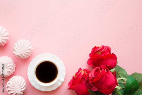 Cup of black coffee with soft, fluffy, airy zephyrs and red roses. Mockup for different ideas. Empty place for positive, sentimental text, lovely quote or sayings on pastel pink table. Top view.