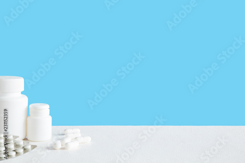 White bottles with pills. Mock up for special offers as advertising or other ideas. Medical, pharmacy and healthcare concept. Copy space. Empty place for text or logo on blue background.