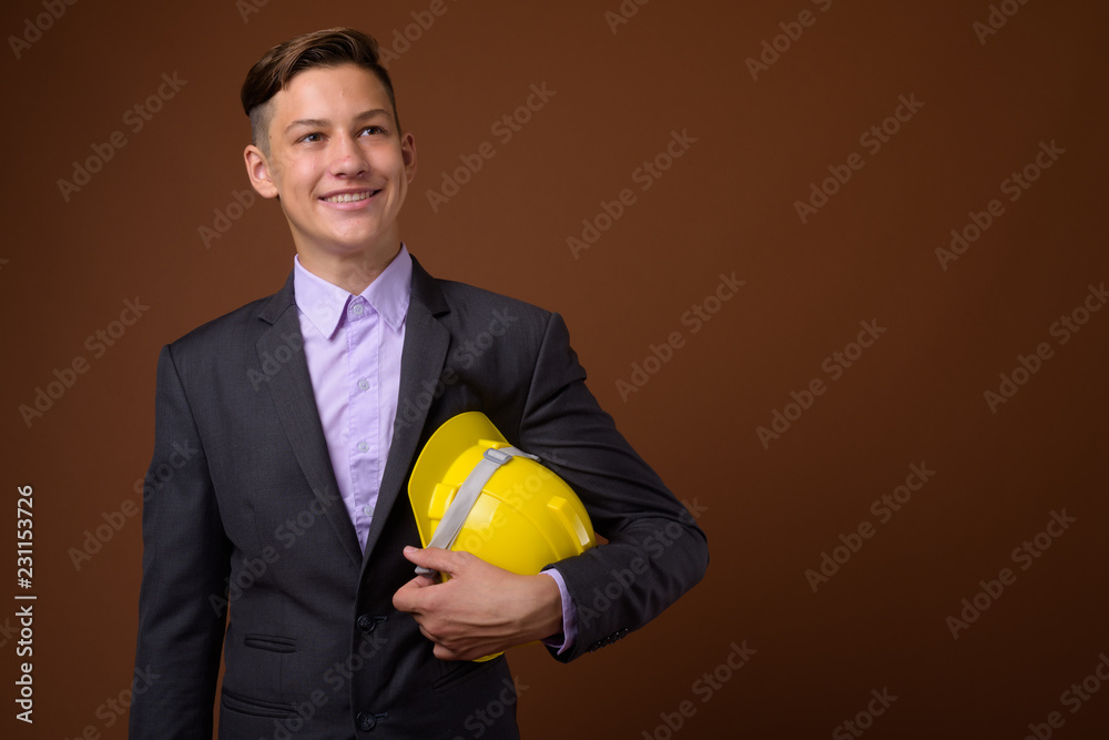 Studio shot of young handsome businessman against brown backgrou