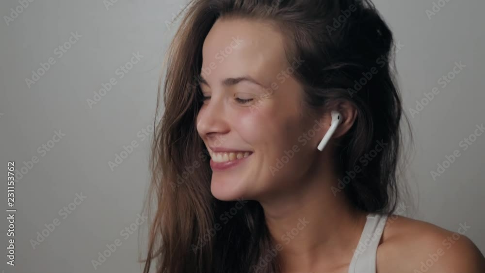 Portrait of a beautiful young, in a leather jacket with airpods in her ear, listens to music. Student dancing happy earpods handsfree bluetooch girl smiling, looking down. Portrait of a beautiful young, in a leather jacket with airpods in her ear, listens to music. Student dancing happy earpods handsfree bluetooch girl smiling, looking down.