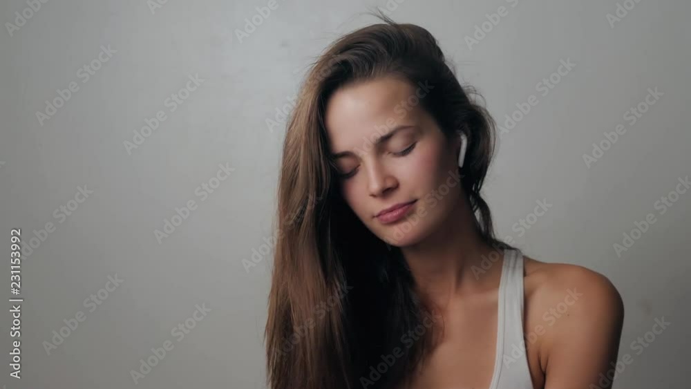 Portrait of a beautiful young, in a leather jacket with airpods in her ear, listens to music. Student dancing happy earpods handsfree bluetooch girl smiling, looking down. Portrait of a beautiful young, in a leather jacket with airpods in her ear, listens to music. Student dancing happy earpods handsfree bluetooch girl smiling, looking down.