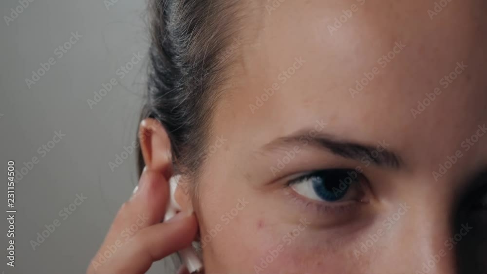 Portrait of a beautiful young, in a leather jacket with airpods in her ear, listens to music close up macro super. Student dancing happy earpods handsfree bluetooch girl smiling, looking down. Portrait of a beautiful young, in a leather jacket with airpods in her ear, listens to music close up macro super. Student dancing happy earpods handsfree bluetooch girl smiling, looking down.