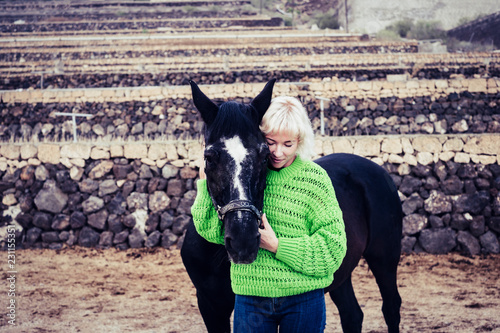 Romance concept image with blonde attractive lonely woman with darj horse in toudoor leisure activity together. Love between humans and animals photo