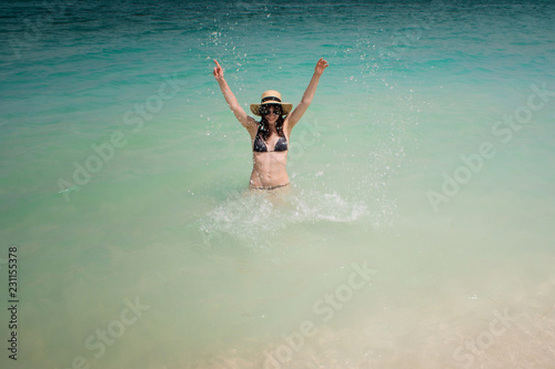 Happy young woman swimming in the azure sea. Funny girl in straw hat
