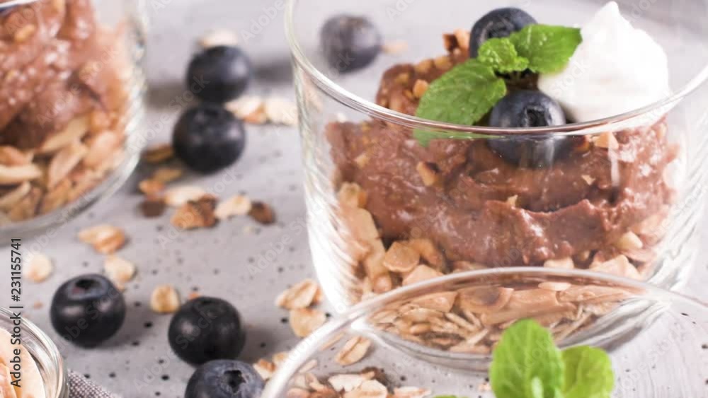 Glass cups of chocolate and chestnuts mousse with roasted almonds and oats decorated with black berries and mint leaves. Glass cups of chocolate and chestnuts mousse with roasted almonds and oats decorated with black berries and mint leaves.