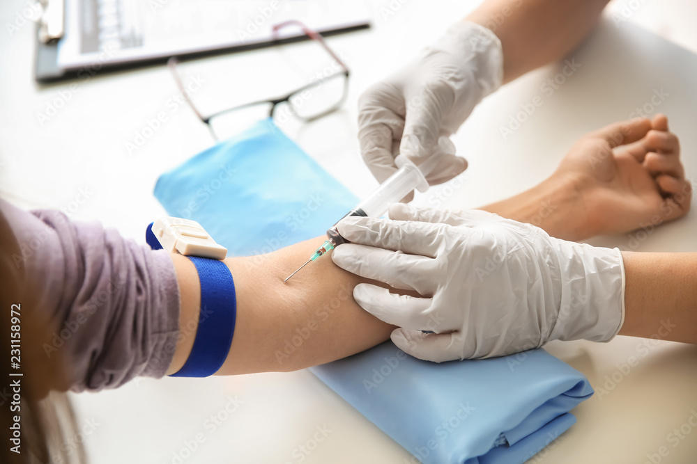 Doctor taking blood sample from vein in hospital Doctor taking blood sample from vein in hospital
