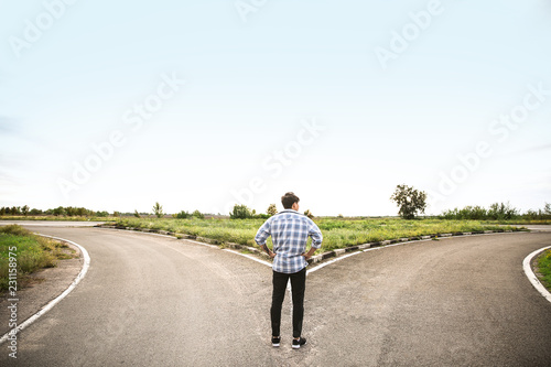 Young man standing at crossroads. Concept of choice