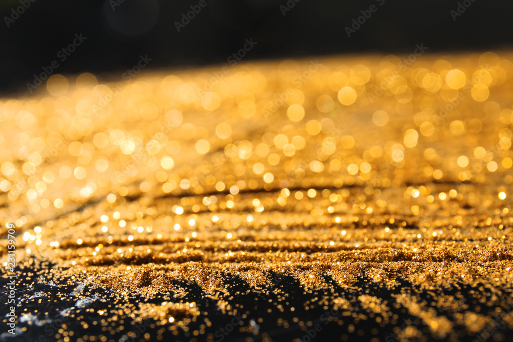 Golden glitters on dark background, closeup