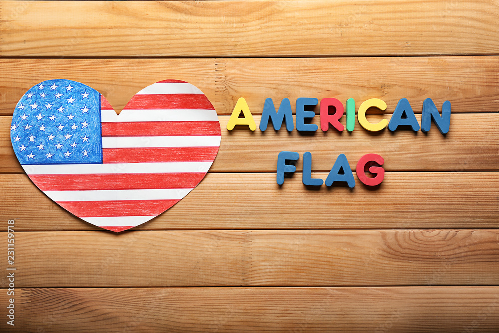 Obraz premium Heart shaped drawing of American national flag with color letters on wooden table