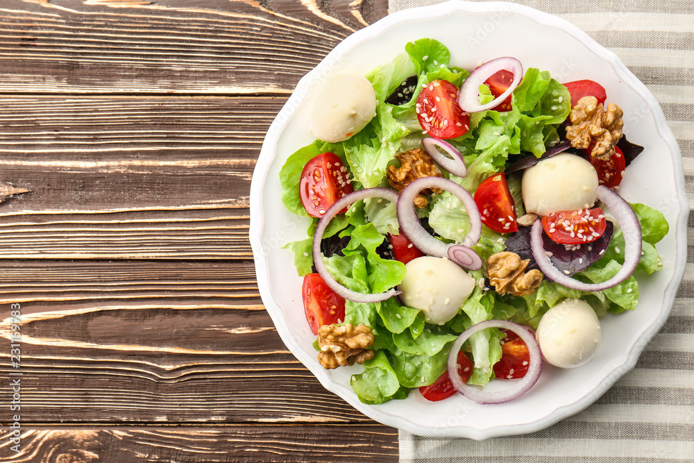 Delicious fresh salad with walnuts on wooden table