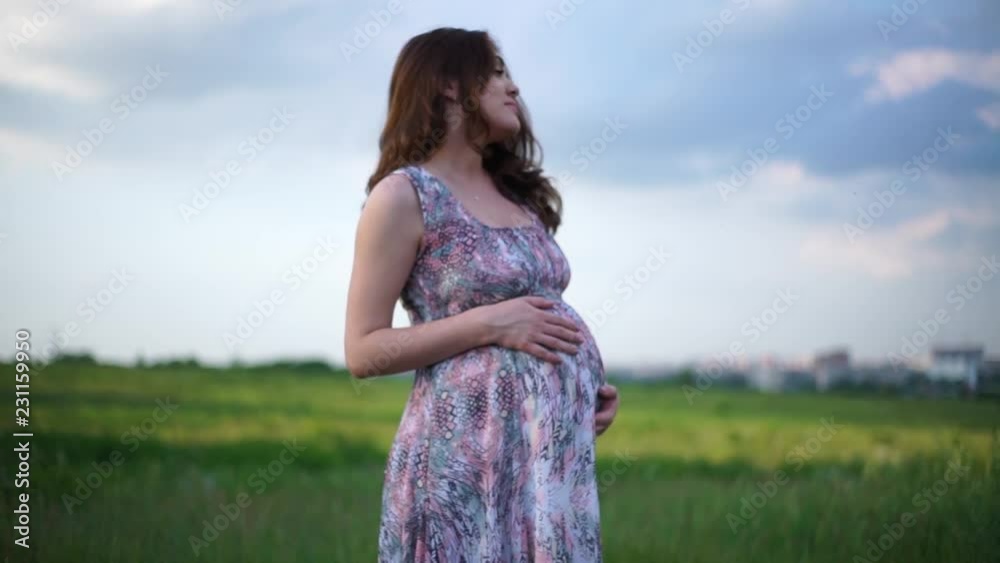 Pregnant girl outdoors stroking her belly Pregnant girl outdoors stroking her belly