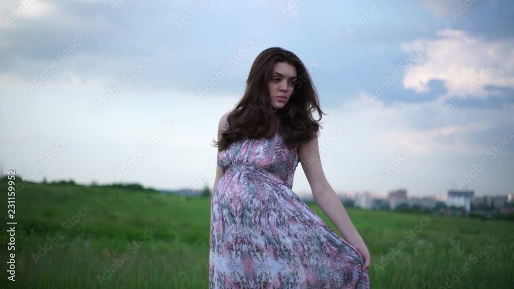 Pregnant girl outdoors stroking her belly and looking into a kamera Pregnant girl outdoors stroking her belly and looking into a kamera