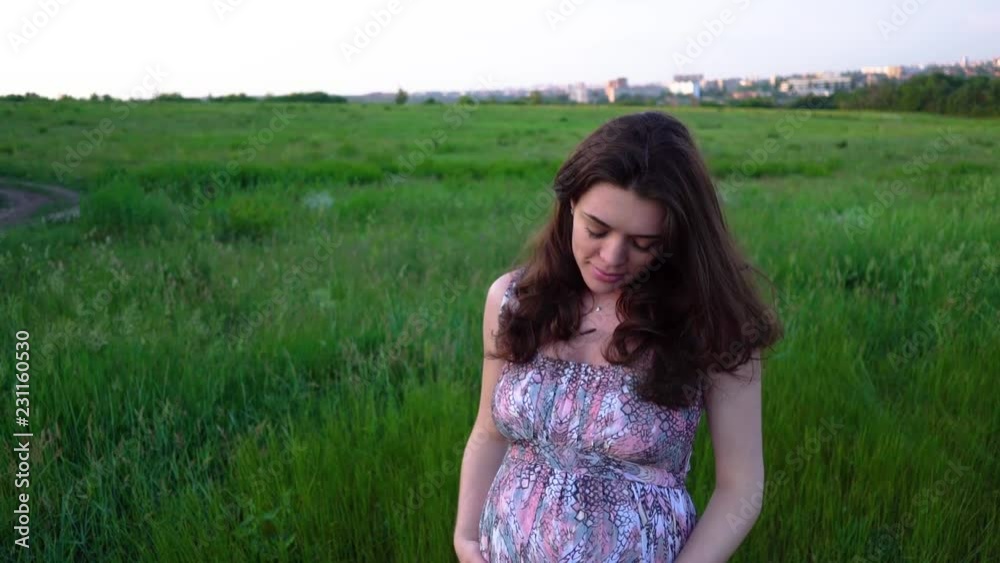 Pregnant girl outdoors stroking her belly Pregnant girl outdoors stroking her belly