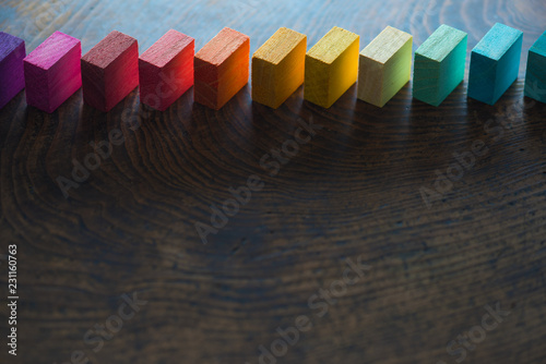 Colored wooden blocks diagonally aligned on old vintage wooden table. For something with concept of variations or diversity. Plenty of copyspace for cover / header image usage. Shallow depth of field. photo