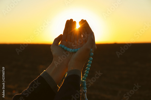 Photography Young Muslim woman praying with beads outdoors at sunrise