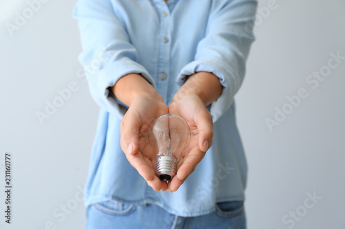 Fényképezés Woman with eco light bulb on light background, closeup