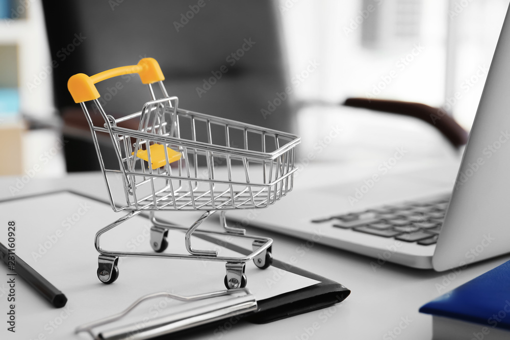 Small cart and laptop on table. Internet shopping concept