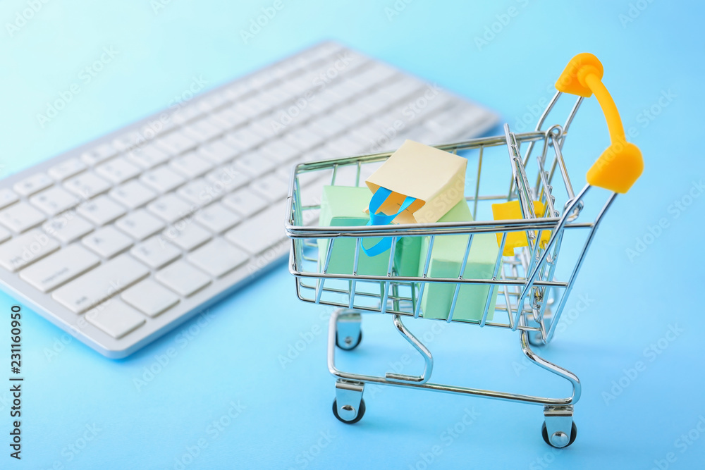Small cart and computer keyboard on table. Internet shopping concept