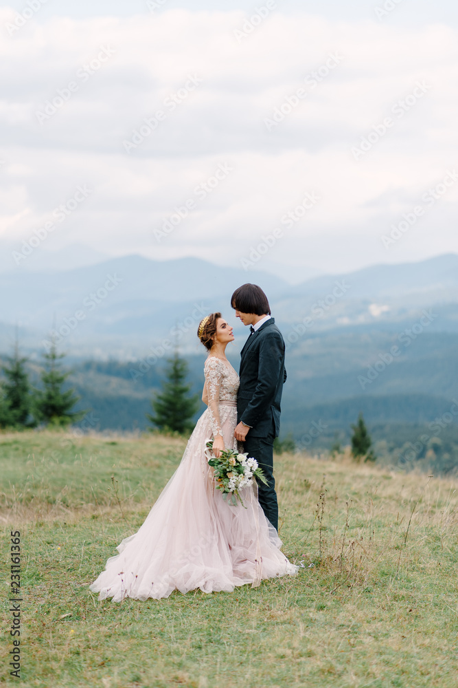 Stylish young bride and groom stand in boat on background cloude sky sea and mountains of Montenegro