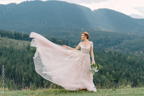 Foto whirling bride holding veil skirt of wedding dress at pine forest