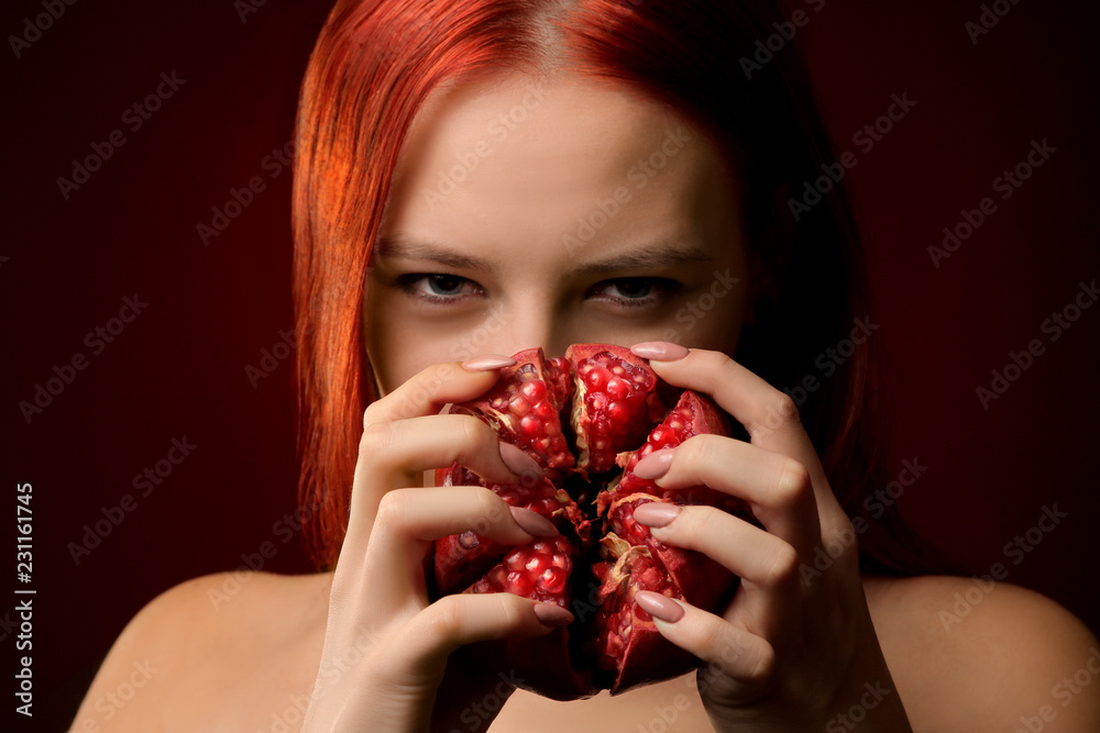 portrait of a young girl with red hair and pomegranate fruit covering her face on a red background portrait of a young girl with red hair and pomegranate fruit covering her face on a red background