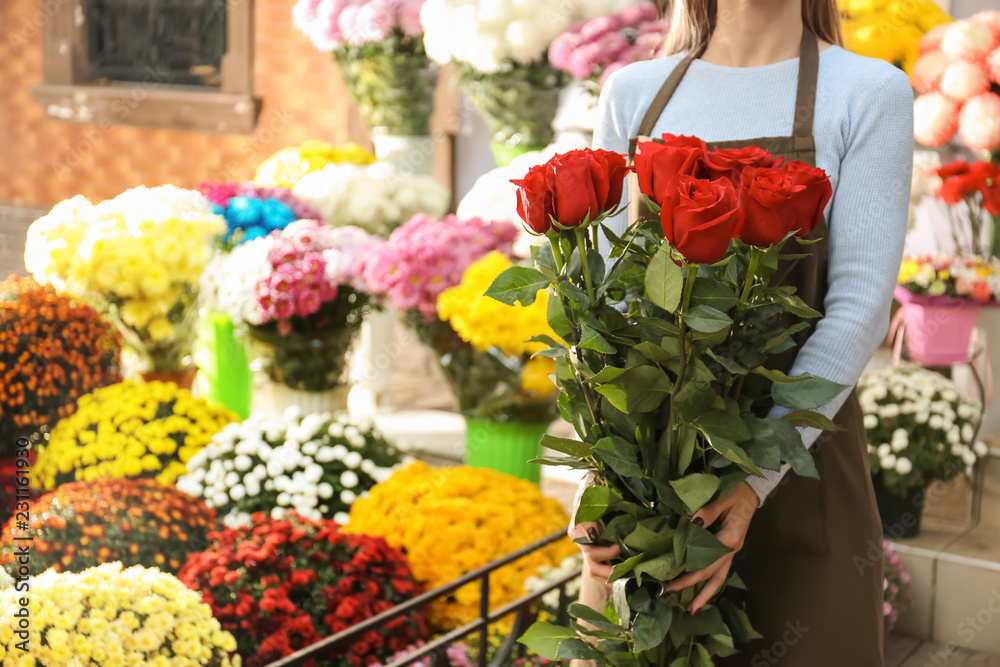 Saleswoman holding bouquet of beautiful roses in shop