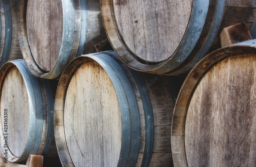 Wooden barrels stacked in a pile with vintage wine at a vineyard