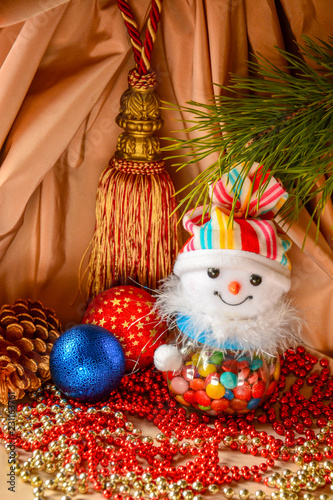 Little toy snowman on the background of the fir branch and Christmas decorations